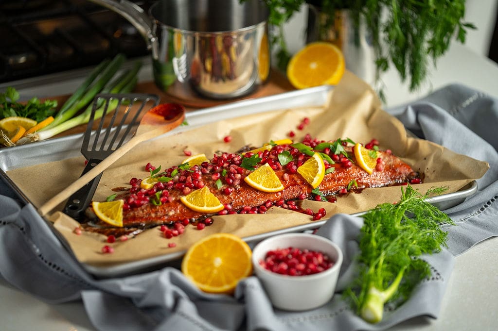 Baked sockeye salmon side, covered in a pomegranate and orange glaze. Baked in the oven and topped with pomegranate seeds, orange and herbs.