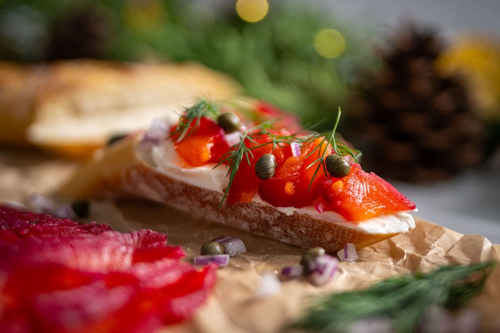 Cured chinook salmon beetroot gravlax, thinly sliced and served on a piece of baguette with cream cheese, capers, red onion and dill.