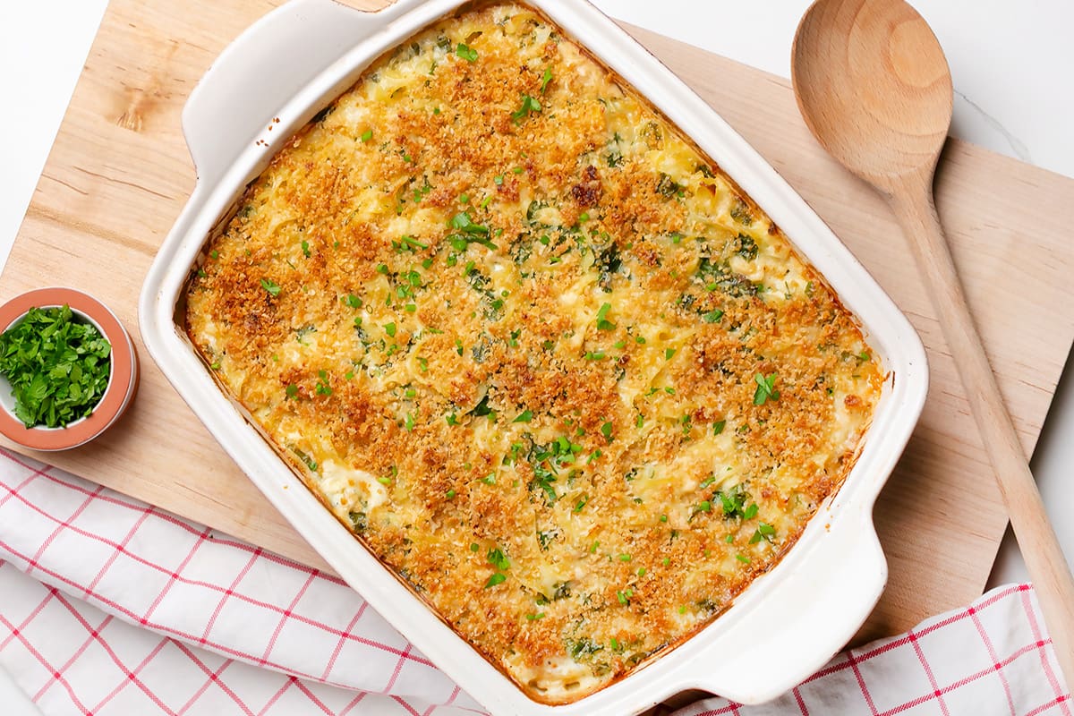 A creamy kale and cauliflower tuna casserole served in a dish with a side of fresh parsley.