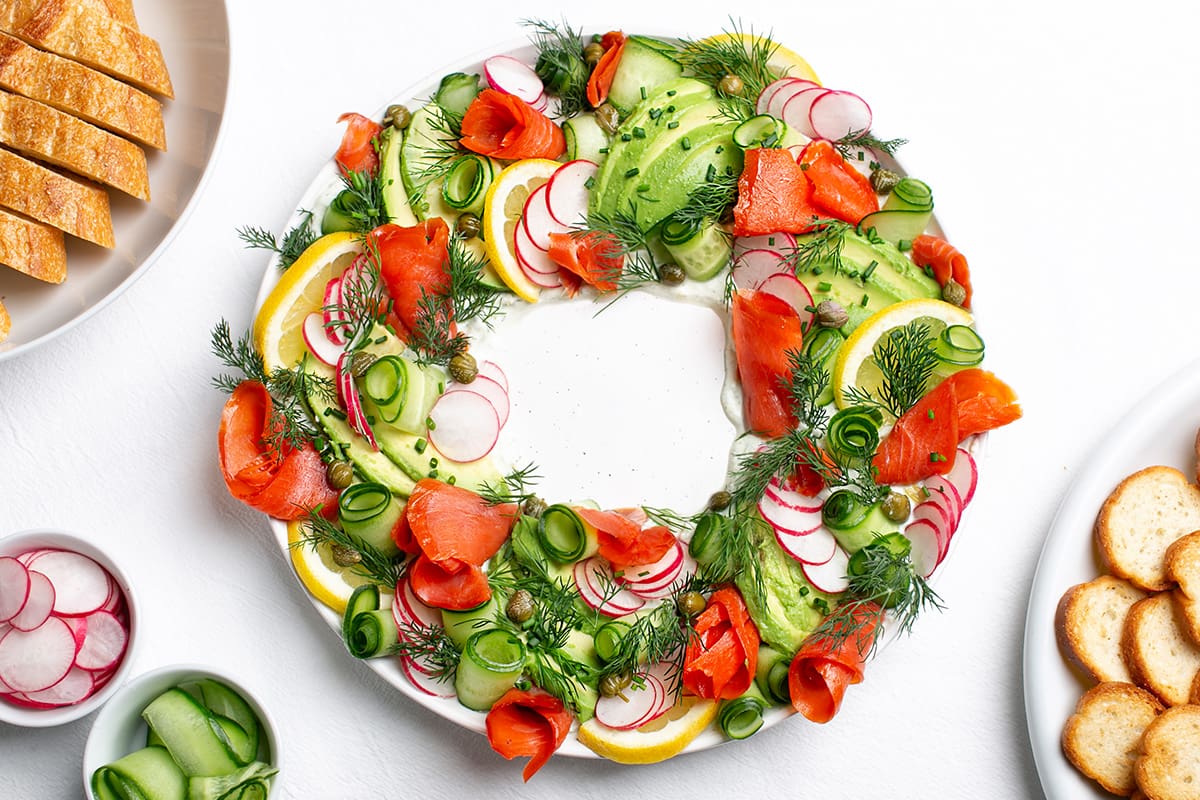 A wreath-like arrangement made with smoked sockeye salmon lox, avocado, radish, cucumber, lemon, capers and dill.
