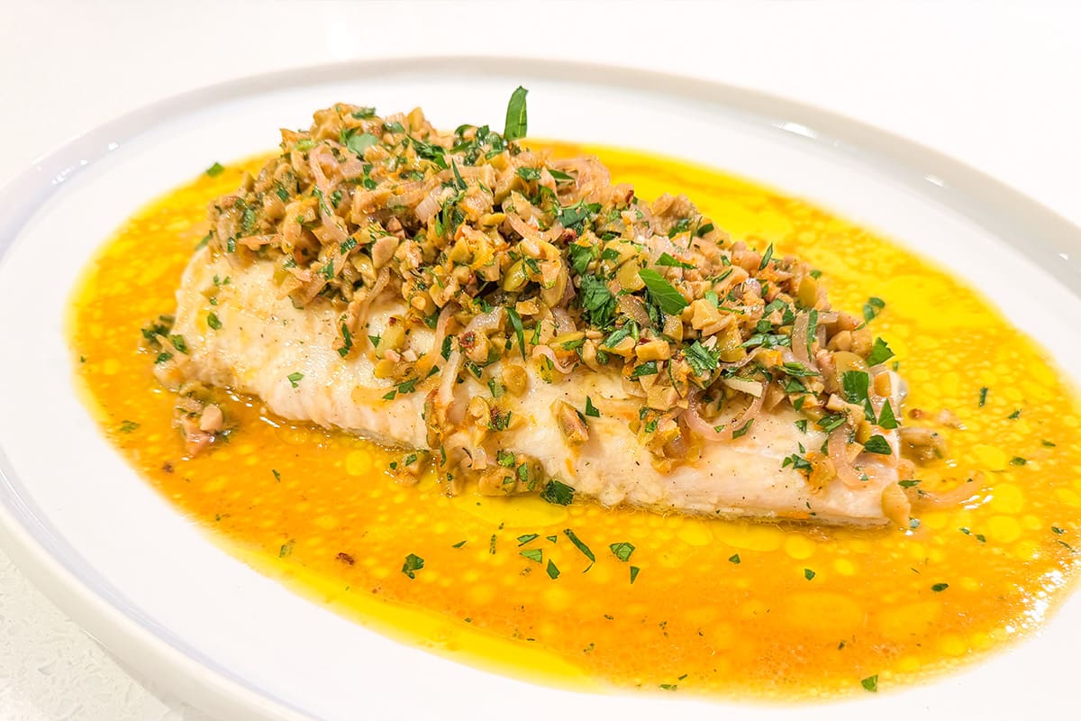 A fillet of oven roasted lingcod topped with olive and orange tapenade.