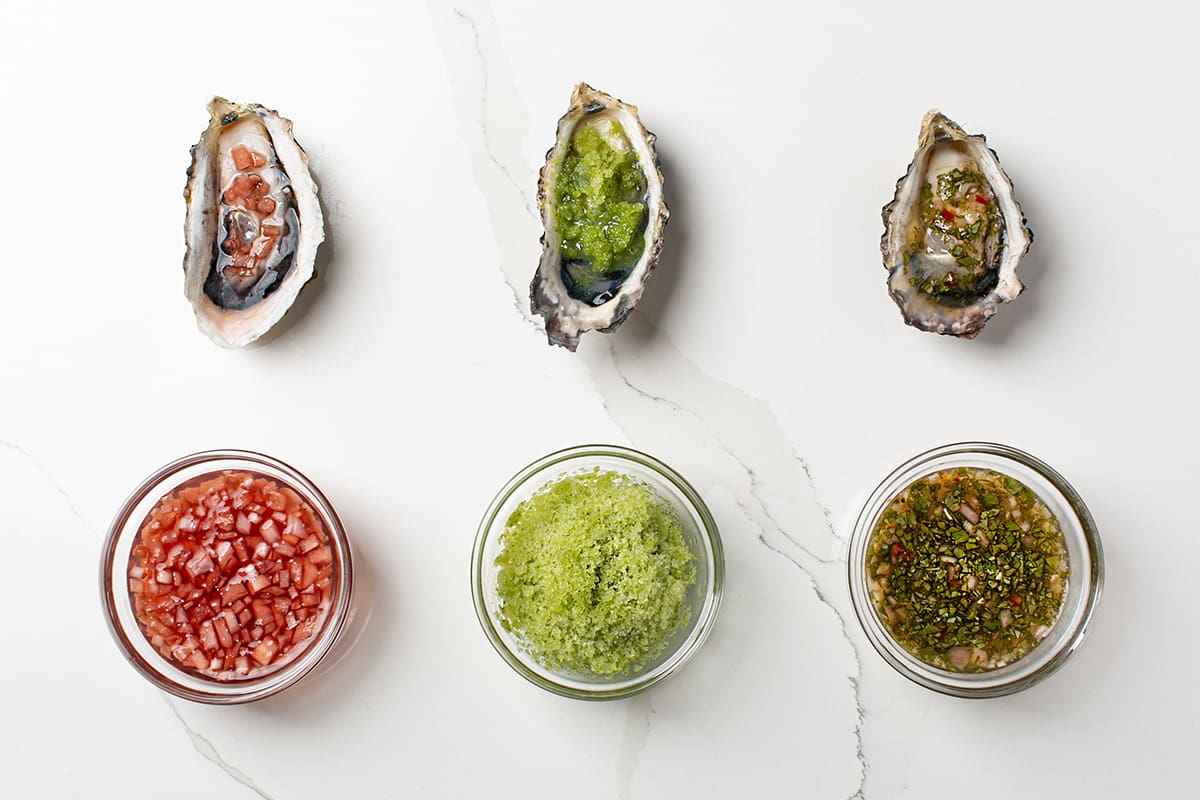 Three Pacific oysters arranged in a row with three types of toppings.