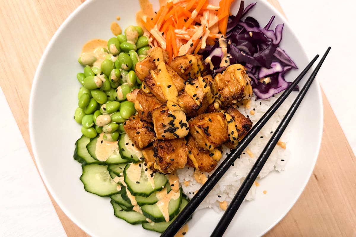 Asian-inspired, air-fried salmon bites served with rice, red cabbage, cucumber, edamame, carrot and sriracha mayonnaise.