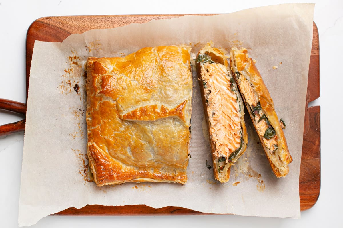 An Arctic char Wellington served on a wooden board.