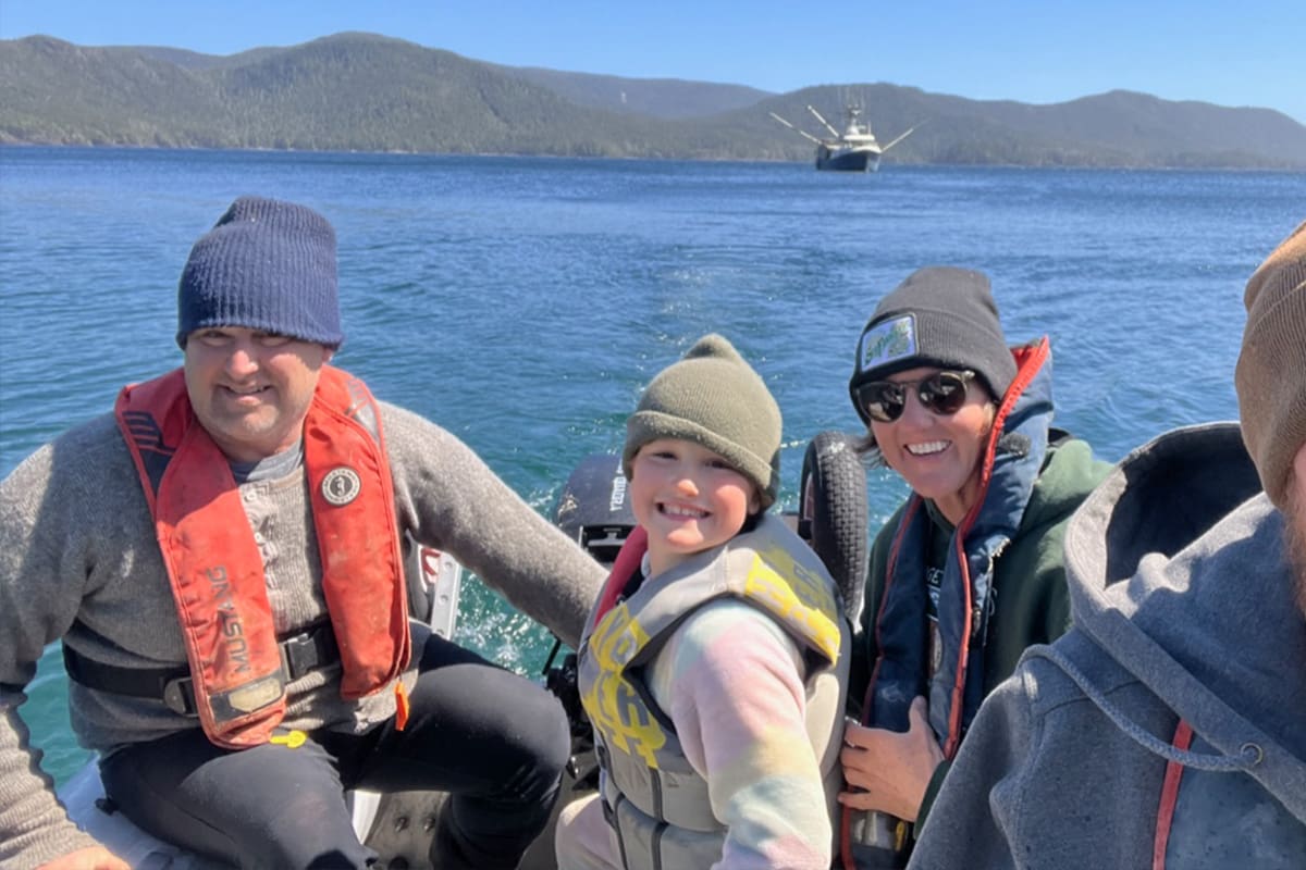 Bruce, Pilar and Rex in a boat heading to shore.